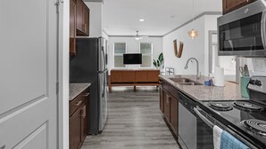 A modern kitchen with a central island, stainless steel appliances, and wooden cabinets.