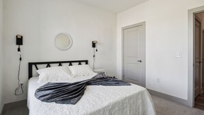 A bedroom with a bed, bedside lamps, a mirror, and a door. - Overlook 4302 I Stunning 2Bd/2Bth Apt I Pool (Knoxville)