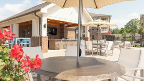 An outdoor patio with a round table and chairs, a brick barbecue area, and a covered seating area with umbrellas. - Overlook 4302 I Stunning 2Bd/2Bth Apt I Pool (Knoxville)