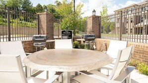 An outdoor patio with a round table and white chairs, surrounded by a brick wall and metal fencing. - Overlook 4302 I Stunning 2Bd/2Bth Apt I Pool (Knoxville)