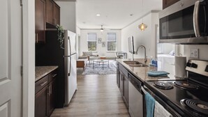 A modern kitchen with dark wooden cabinets, stainless steel appliances, and a central island. - Overlook 7207 I Modern and Spacious 2Bd Apt (Knoxville)