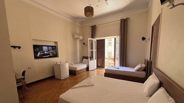 A hotel room with a large bed, a TV, a desk, and a view of the outside.
