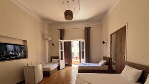 A hotel room with a bed, a desk, a TV, and a window with curtains.