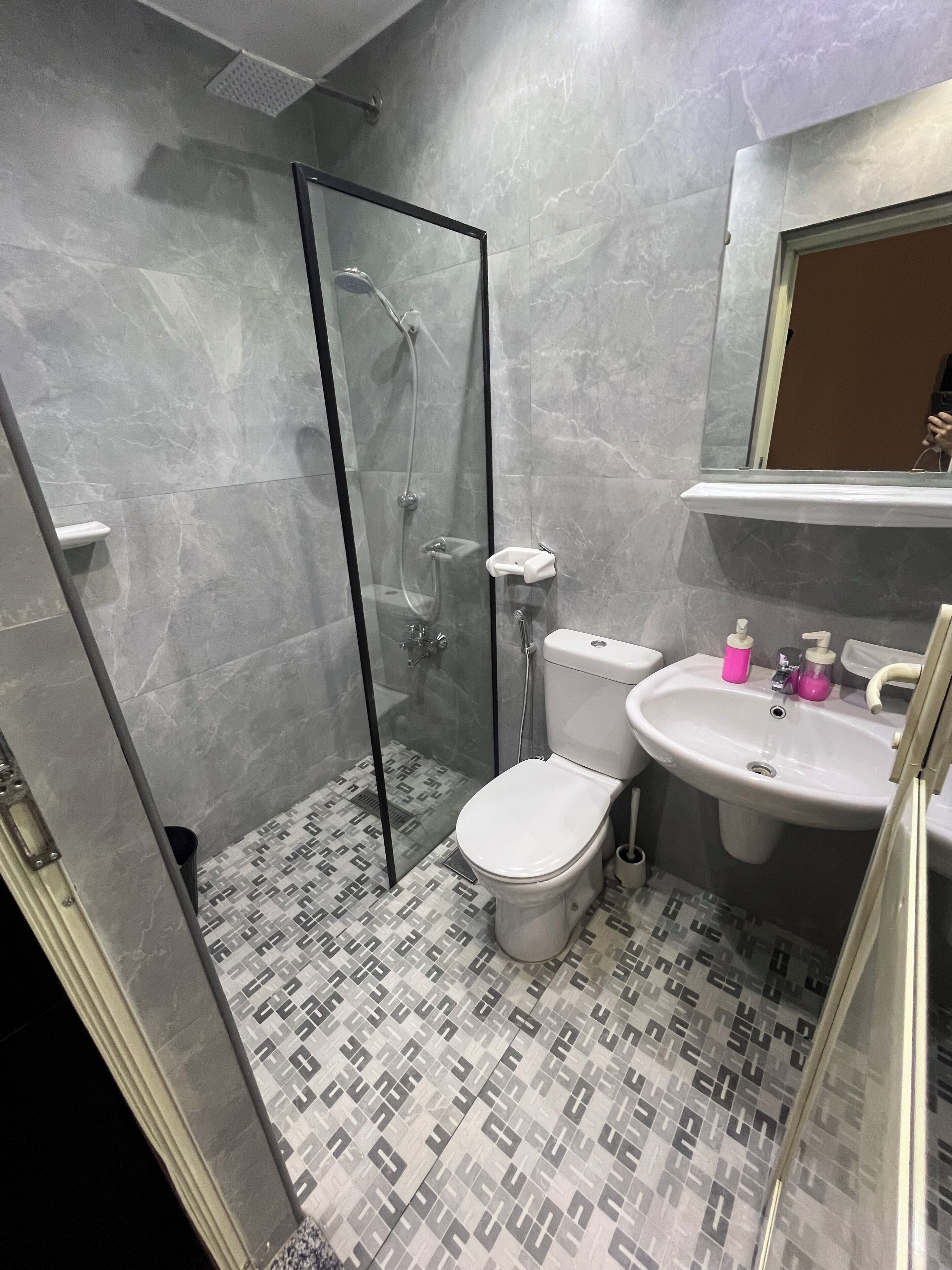 A bathroom with a glass-enclosed shower, a toilet, and a sink.