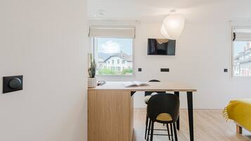 A modern, minimalist room with a wooden desk, a black chair, and a yellow bed.