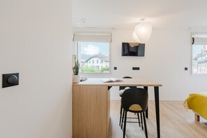 A modern, minimalist room with a wooden desk, a black chair, and a yellow bed. - 108 - Appart'Hôtel Neostelia-Annecy (Annecy)