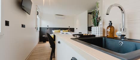 A modern kitchen with a wooden countertop, black sink, and a built-in TV.