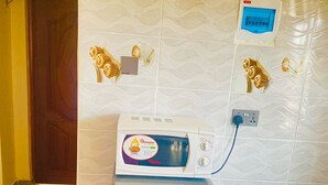 Ein kleiner Kühlschrank mit Bedienfeld, einer Steckdose und einem an der Wand montierten Thermostat.