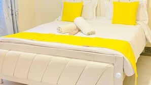 Ein Bett mit weißem Kopfteil und zwei gelben Kissen, einer weißen Bettdecke und einer gelben Decke.