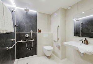 A modern bathroom with a shower, toilet, and sink, featuring marble walls and a large mirror. - 109 - Appart'Hôtel Neostelia-Annecy (Annecy)