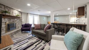 Een moderne woonkamer met een stenen openhaard, een zithoek, een eethoek en een keuken.