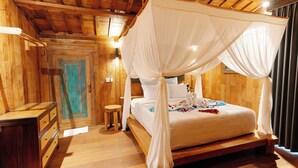 Un dormitorio tipo cabaña de madera con una cama con dosel, un aparador de madera y un taburete pequeño.