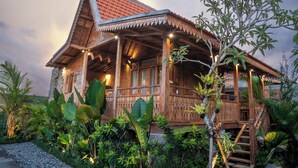 Una casa de madera con techo de tejas, rodeada de exuberante vegetación tropical.