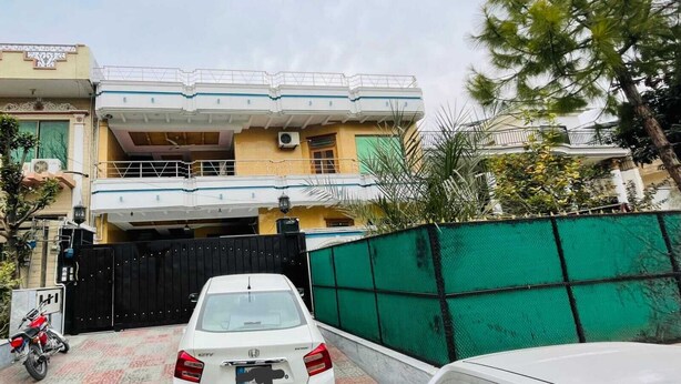 A two-story residential building with a gated entrance, a parked white car, and a motorcycle. - Istanbul Inn Guest House (Islamabad)