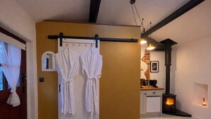 Ein Zimmer mit einer weißen Tür, einem weißen Handtuch an einem Haken, einem weißen Schrank, einem schwarzen Herd und einer Pendelleuchte.