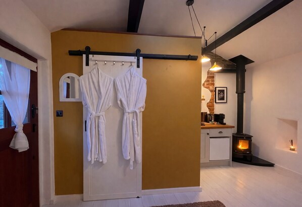 A room with a white door, a white towel hanging on a hook, a white cabinet, a black stove, and a hanging light fixture. - Little Gem at Lough Sillan House | Romantic, Adults only with hot tub and sauna (Shercock)
