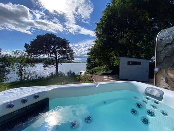 A hot tub with a view of a lake and trees.