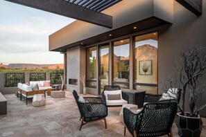 A modern outdoor patio with seating, large windows, and a view of the mountains. - Red Rock Luxe Villa: Pool, Spa, Views, Private Courtyard (Sedona)