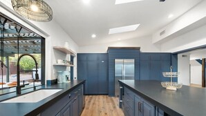 Una cucina moderna con mobili scuri blu, un'isola centrale e un frigorifero integrato.