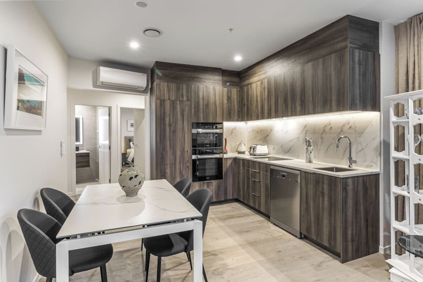 A modern kitchen with dark wood cabinets, a white countertop, and a built-in oven.