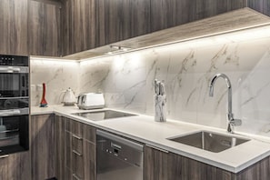 A modern kitchen with a built-in dishwasher, a double sink, and a stainless steel faucet.