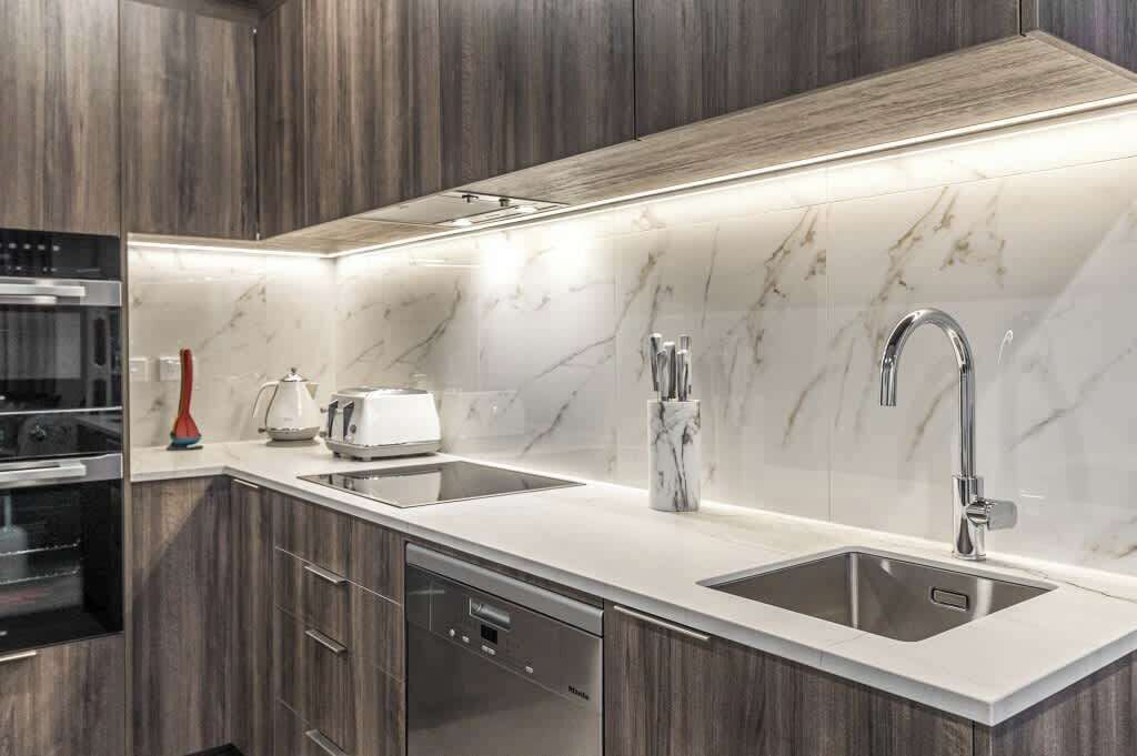 A modern kitchen with a double sink, built-in oven, and a dishwasher.