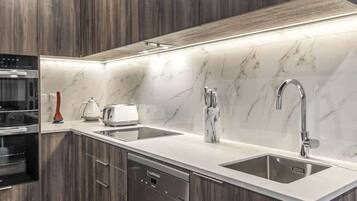 A modern kitchen with a double sink, built-in oven, and a dishwasher.