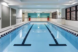 An indoor swimming pool with a checkered edge, a central lane divider, and potted plants on either side. - Stylish Apt with Views Pool and Gym - Zodiak Stays (Auckland)