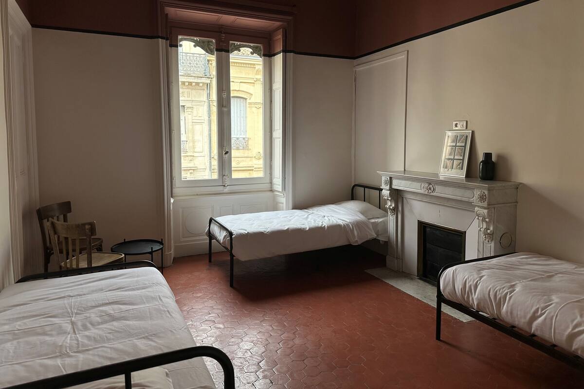Een slaapkamer met twee eenpersoonsbedden, een tafeltje, een stoel en een open haard.