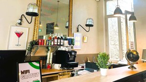 Un espace bar agrémenté d’un grand miroir, de diverses bouteilles, d’une enseigne indiquant que le Wi-Fi est gratuit, et d’une fenêtre laissant entrer la lumière naturelle.