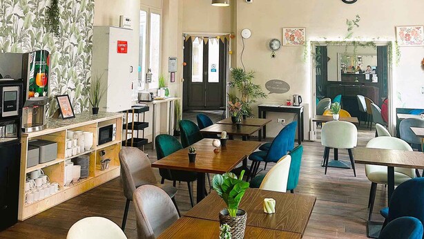 Un café avec des tables en bois, des chaises bleues et des plantes en pot.