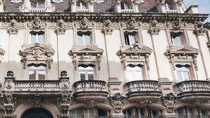 Un bâtiment historique doté d’éléments architecturaux raffinés, notamment des balcons décoratifs et des fenêtres de style classique.
