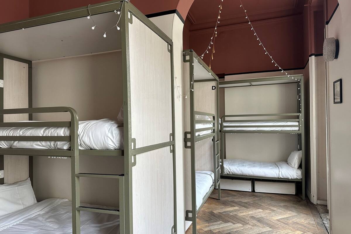 Een slaapkamer met een stapelbed, een houten visgraatvloer en een witte muur.