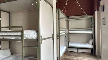 Habitación con literas, suelo de madera en patrón de espiga y pared blanca.