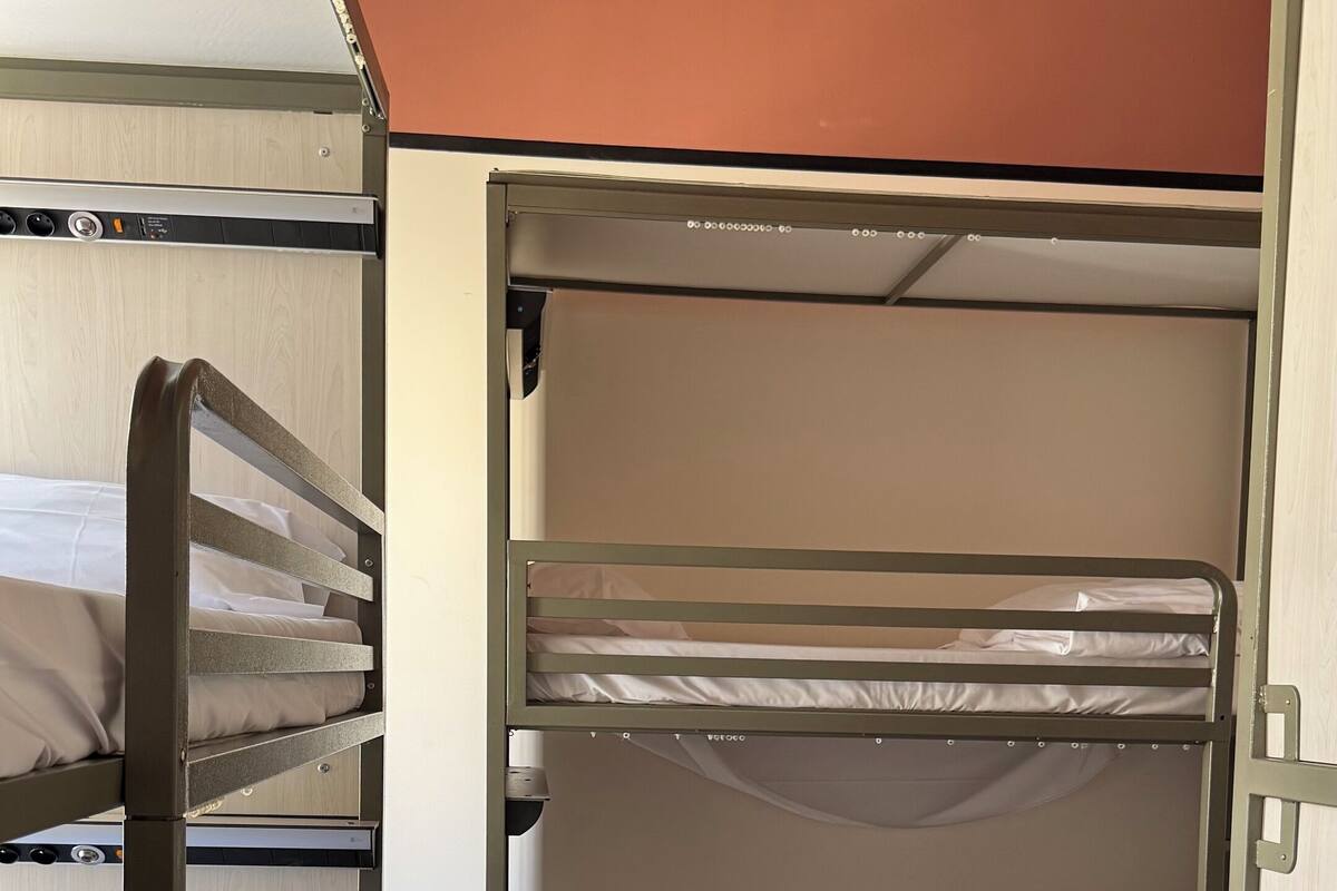 Een slaapkamer met een stapelbed, een houten vloer en een bruin plafond.