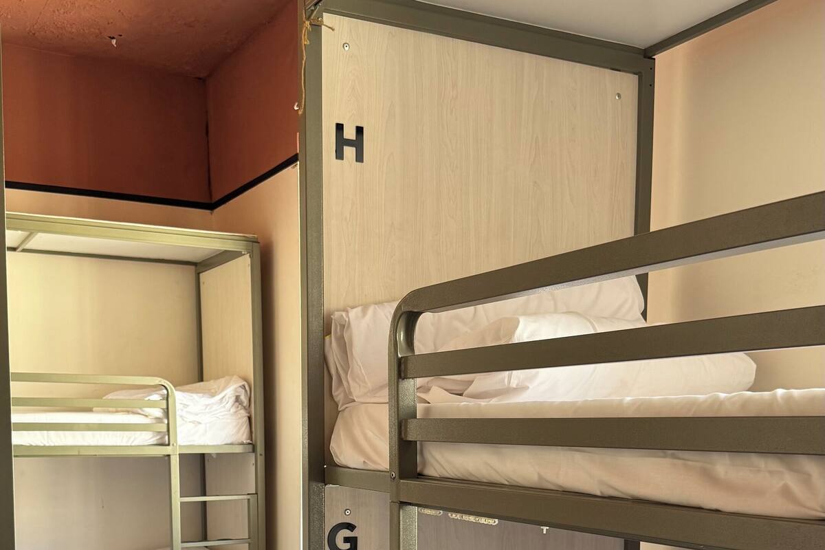 Een slaapkamer met een stapelbed en een houten deur met de letter 'H' er op.