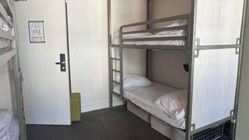 Un dormitorio tipo litera con literas, una puerta y un equipo de aire acondicionado.
