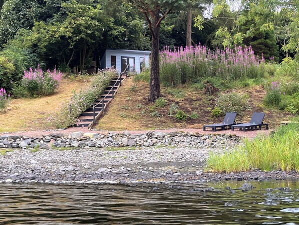 A lakeside property with a wooden deck, a stone pathway, and a small building with a door. - Linden Lodge at Lough Sillan House  dog-friendly, adults-only, lakeside retreat (Shercock)