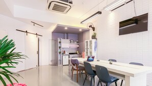 Een moderne keuken met witte kastjes, een centraal eiland en een eethoek met stoelen.