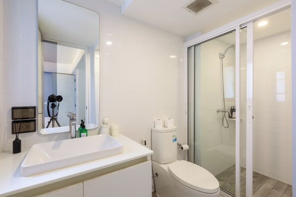 Une salle de bain moderne avec un lavabo blanc, des toilettes et une douche à parois de verre.