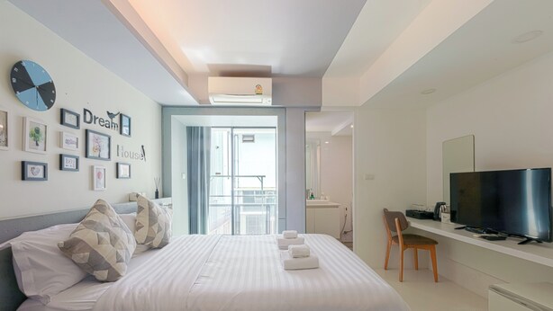 Een moderne hotelkamer met een bed, een televisie, een bureau en een balkon.