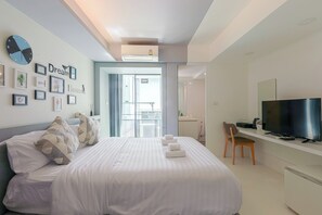 Une chambre d’hôtel moderne équipée d’un lit, d’une télévision, d’un bureau et d’un balcon.