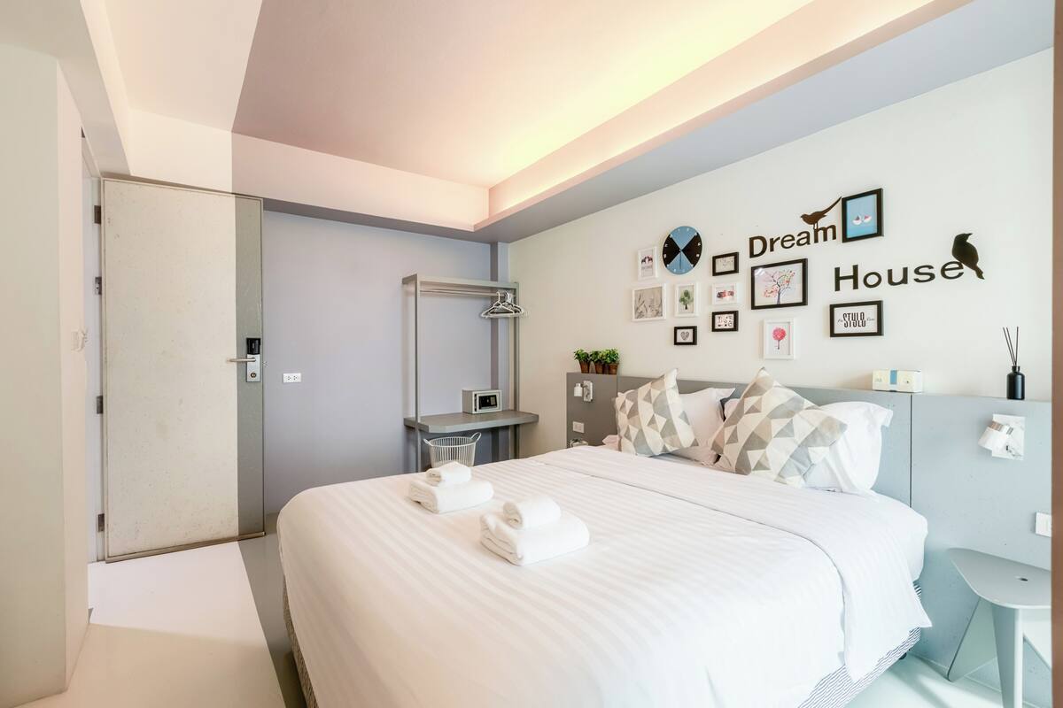 Moderni hotellihuone, jossa on suuri sänky, työpöytä ja suihkutila.