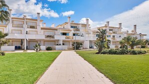 A multi-story residential building with a central courtyard, balconies, and a paved walkway. - Apartment O Monte with pool and tennis court  (Guia)