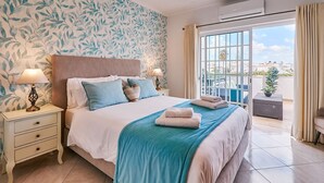 A hotel room with a bed, nightstands, a window with curtains, and a view of the outside. - Apartment O Monte with pool and tennis court  (Guia)