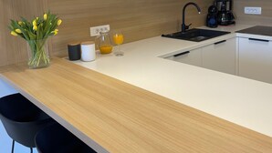 Een moderne keuken met witte kastjes, een houten aanrecht, een koffiezetapparaat en een vaas met gele bloemen.