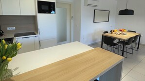 Een moderne keuken met witte kasten, een houten aanrecht en een eethoek met een tafel en stoelen.