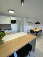 Una cocina moderna con armarios blancos, encimera de madera y un comedor con mesa y sillas.