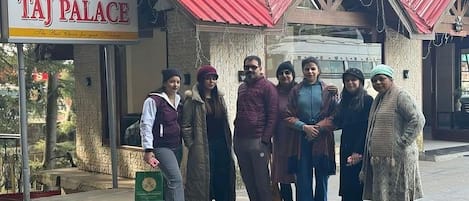 A group of people standing in front of a building with a sign that reads "HOTEL TAJ PALACE".