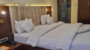A hotel room with a large bed, a wooden headboard, a bedside table with a lamp, and a wardrobe. - Hotel Taj palace Dalhousie (Dalhousie)